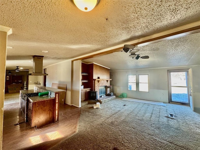 living room with dark carpet, ceiling fan, baseboard heating, crown molding, and a brick fireplace