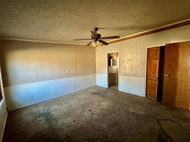 unfurnished bedroom featuring ceiling fan, ensuite bath, carpet flooring, and a textured ceiling