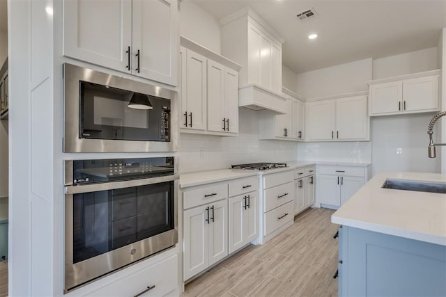 kitchen featuring built in microwave, sink, and white cabinets