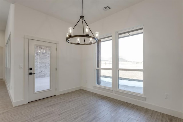 unfurnished dining area with a notable chandelier and light wood-type flooring