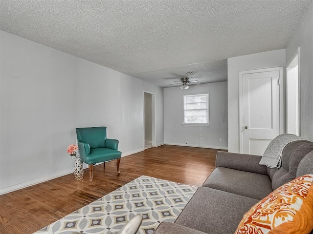 living room featuring ceiling fan, hardwood / wood-style flooring, and a textured ceiling