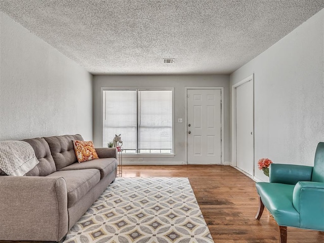 living room featuring wood-type flooring and a textured ceiling