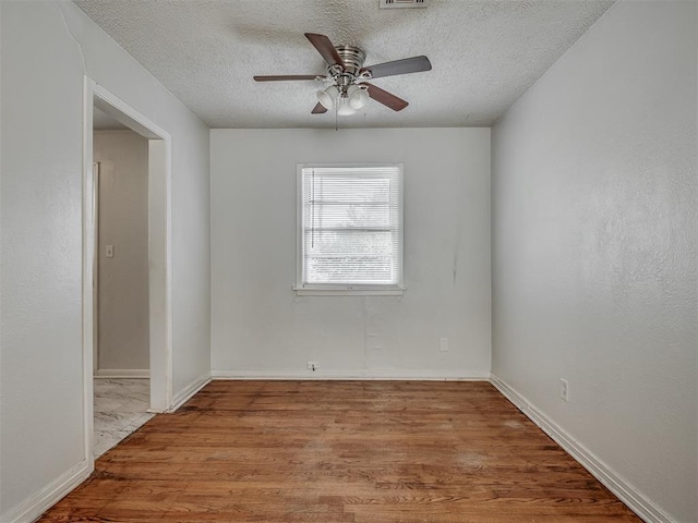 empty room featuring ceiling fan, a textured ceiling, and light wood-type flooring