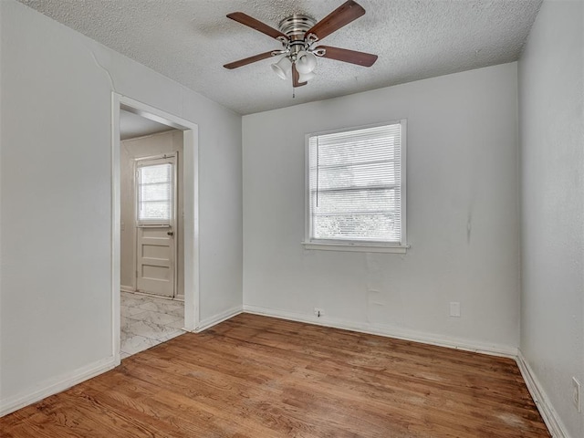 empty room with ceiling fan, a textured ceiling, and light hardwood / wood-style floors