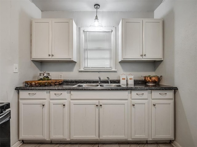 kitchen with pendant lighting, sink, white cabinets, and range