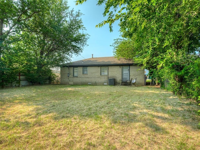 back of house with cooling unit and a yard