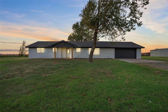 ranch-style home with a garage and a yard