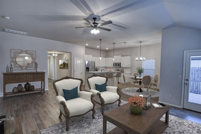 living room with ceiling fan with notable chandelier and dark hardwood / wood-style flooring