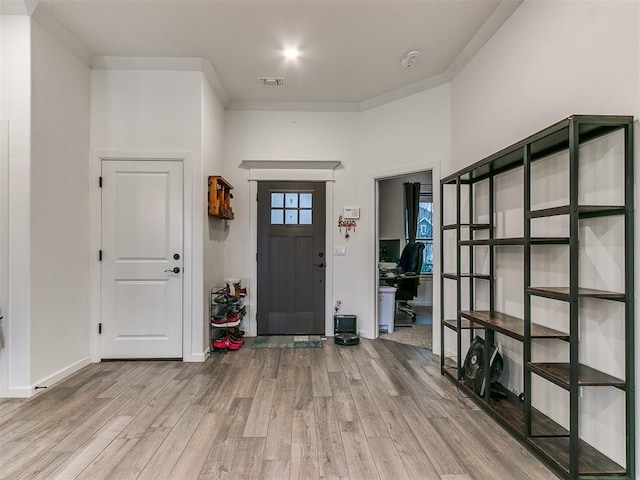 foyer entrance featuring ornamental molding and wood-type flooring