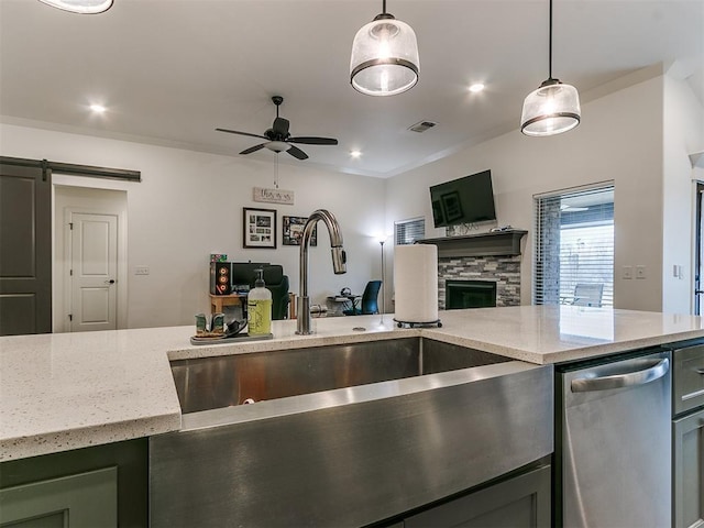 kitchen with a barn door, dishwasher, sink, and hanging light fixtures