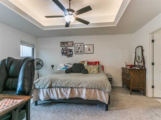 carpeted bedroom featuring ceiling fan and a tray ceiling