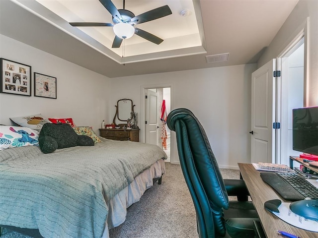 carpeted bedroom with a raised ceiling and ceiling fan