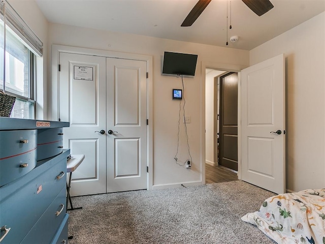 unfurnished bedroom with ceiling fan, dark carpet, and a closet