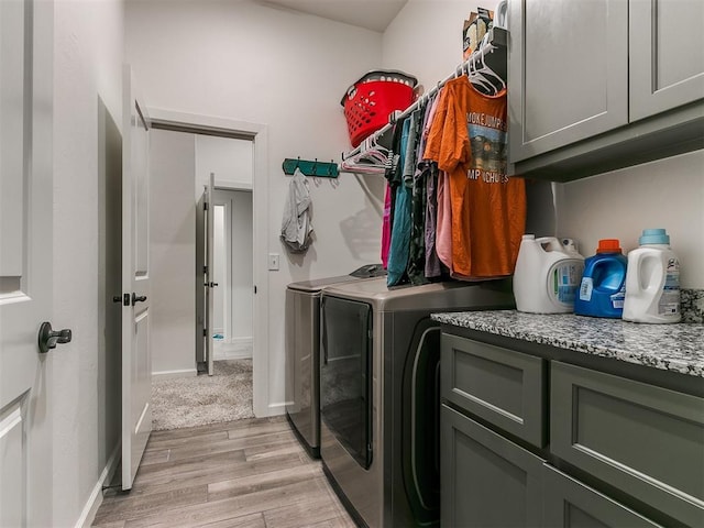 laundry area featuring cabinets, washing machine and dryer, and light hardwood / wood-style flooring