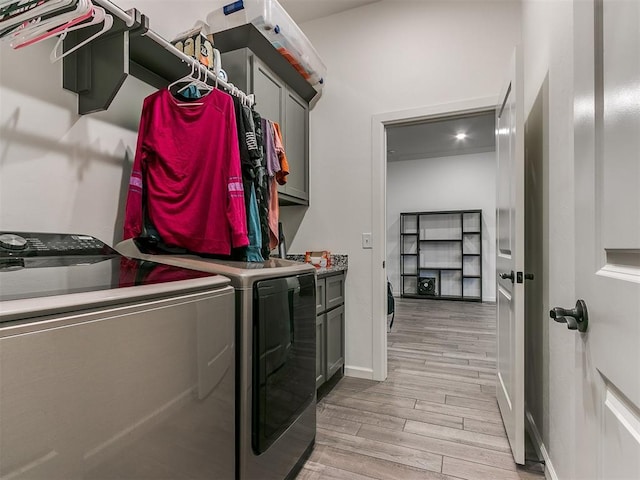 laundry room featuring light hardwood / wood-style flooring, washer and clothes dryer, and cabinets