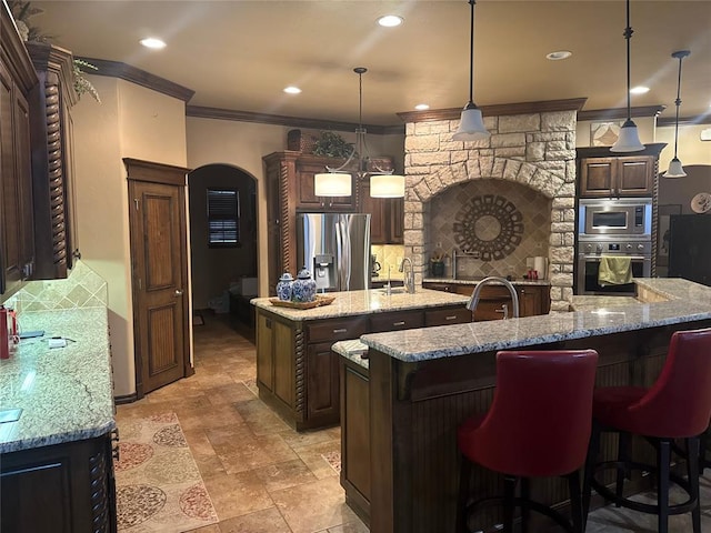 kitchen featuring sink, stainless steel appliances, a spacious island, decorative backsplash, and decorative light fixtures