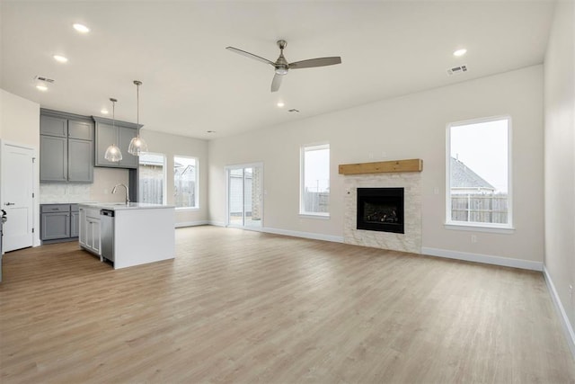 kitchen featuring hanging light fixtures, dishwasher, a kitchen island with sink, and gray cabinets