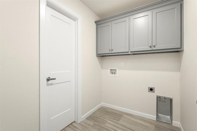 laundry room with electric dryer hookup, washer hookup, cabinets, and light wood-type flooring