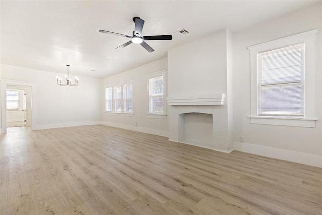 unfurnished living room featuring ceiling fan with notable chandelier and light hardwood / wood-style floors