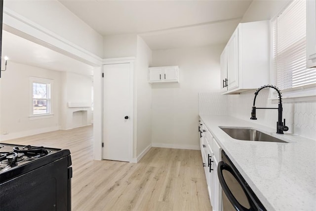 kitchen with white cabinetry, sink, black appliances, light stone countertops, and light hardwood / wood-style flooring