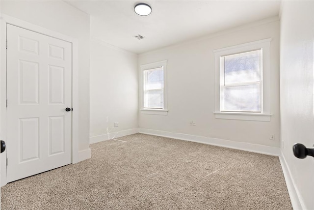 empty room featuring ornamental molding and carpet flooring