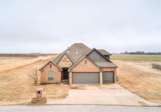 view of front facade featuring driveway, a garage, a rural view, roof with shingles, and brick siding