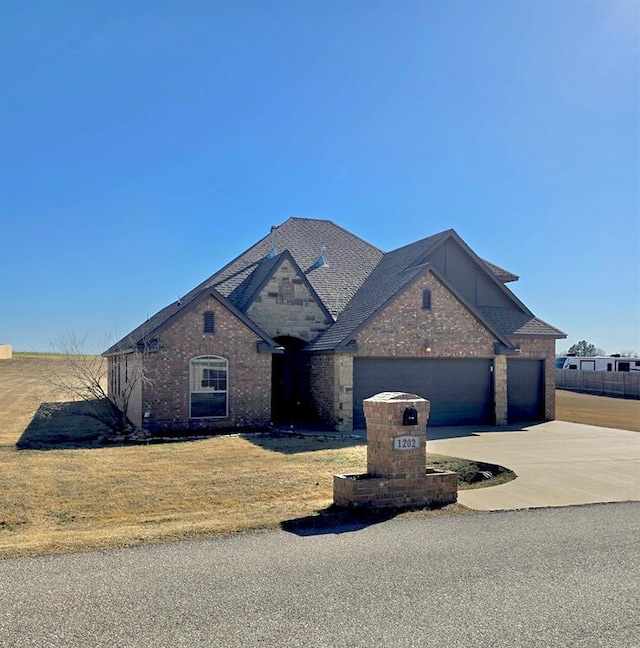 view of front of home with an attached garage, brick siding, driveway, and a front yard