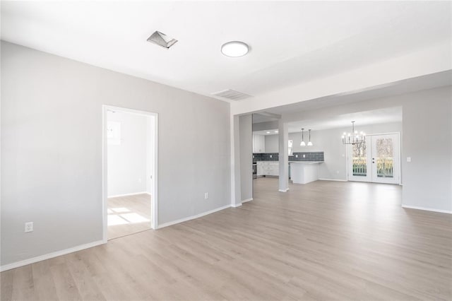 unfurnished living room featuring a notable chandelier and light hardwood / wood-style flooring