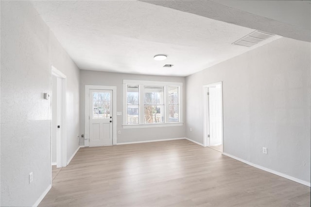 interior space with a textured ceiling and light hardwood / wood-style floors