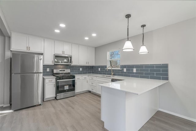 kitchen with sink, white cabinetry, stainless steel appliances, tasteful backsplash, and kitchen peninsula