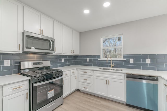 kitchen featuring white cabinetry, stainless steel appliances, sink, and light hardwood / wood-style flooring