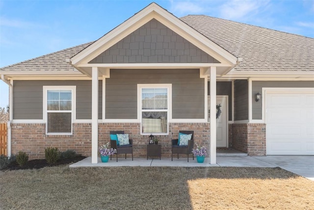 view of front facade featuring an attached garage, roof with shingles, a front yard, and brick siding