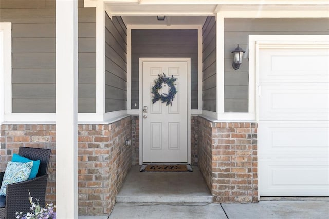 entrance to property featuring a garage and brick siding