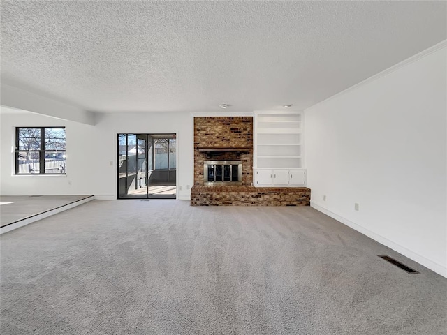 unfurnished living room featuring a fireplace, carpet floors, built in features, and a textured ceiling