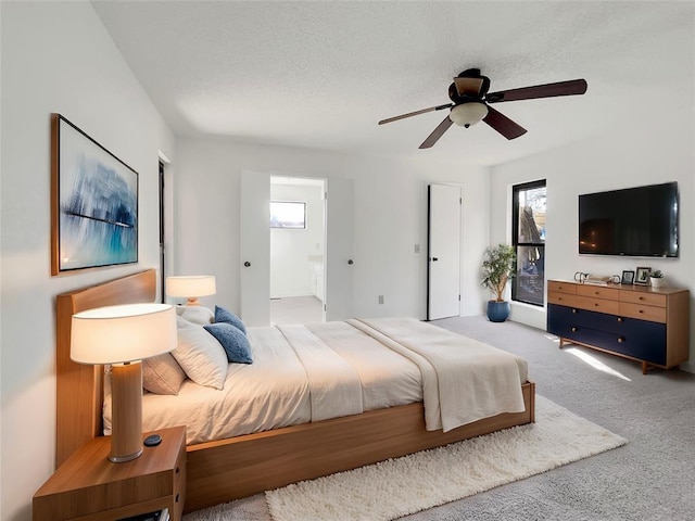 carpeted bedroom featuring a textured ceiling, ceiling fan, and ensuite bath