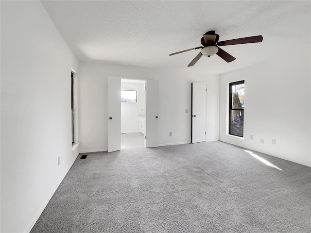 carpeted empty room with ceiling fan and a textured ceiling