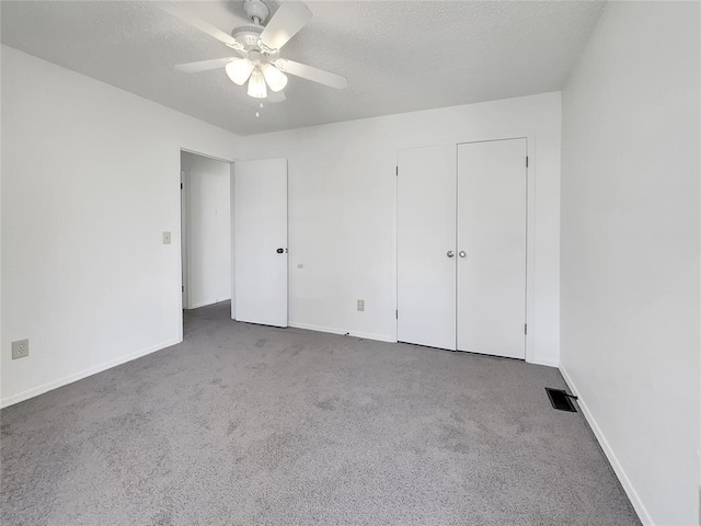 unfurnished bedroom with ceiling fan, dark carpet, and a textured ceiling