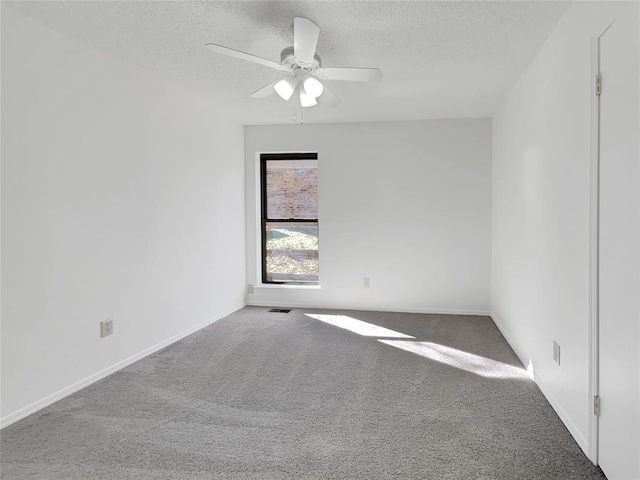 carpeted spare room featuring ceiling fan and a textured ceiling