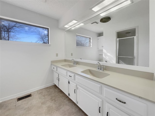 bathroom featuring vanity, tile patterned flooring, a textured ceiling, and walk in shower