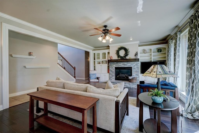 living room with a stone fireplace, ornamental molding, dark hardwood / wood-style floors, and ceiling fan