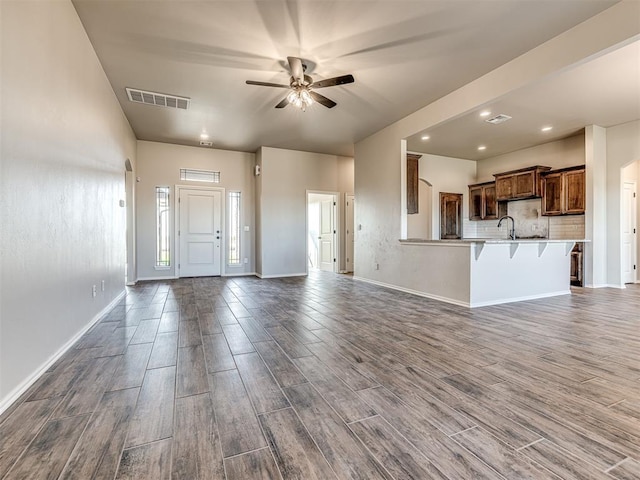 unfurnished living room featuring ceiling fan, sink, and hardwood / wood-style floors