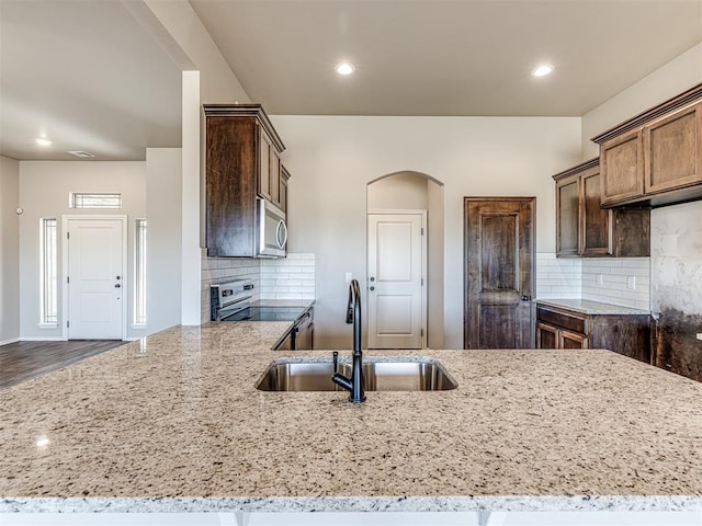 kitchen featuring stainless steel appliances, light stone countertops, sink, and kitchen peninsula