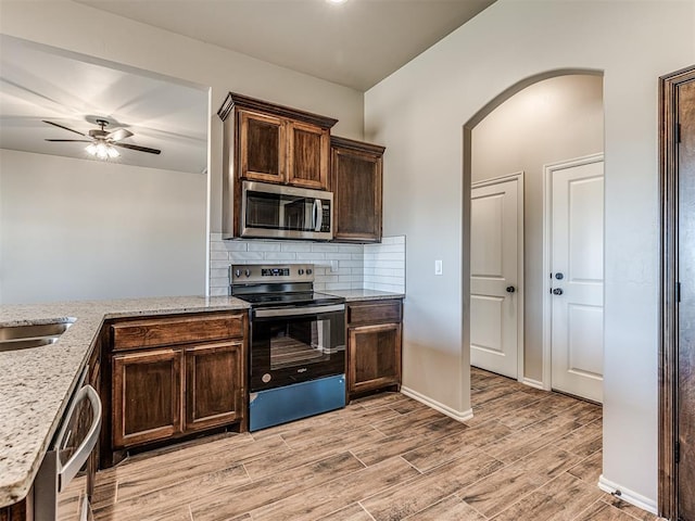 kitchen with light stone counters, decorative backsplash, light hardwood / wood-style flooring, and appliances with stainless steel finishes