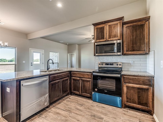 kitchen with tasteful backsplash, appliances with stainless steel finishes, sink, and light stone counters