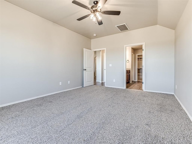 unfurnished bedroom with vaulted ceiling, ceiling fan, ensuite bathroom, and carpet floors