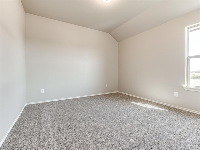 carpeted spare room featuring vaulted ceiling