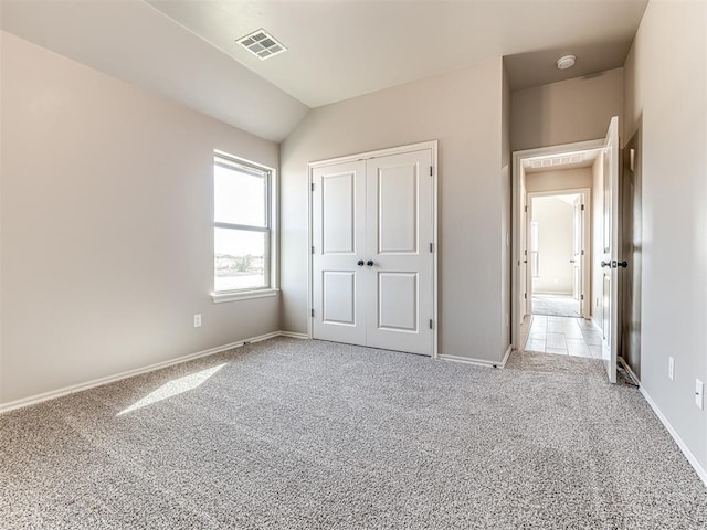 unfurnished bedroom featuring light carpet, vaulted ceiling, and a closet