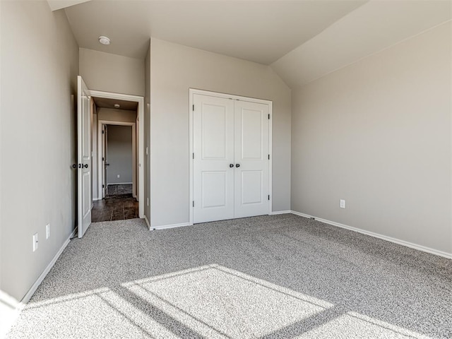 unfurnished bedroom with vaulted ceiling, a closet, and carpet flooring