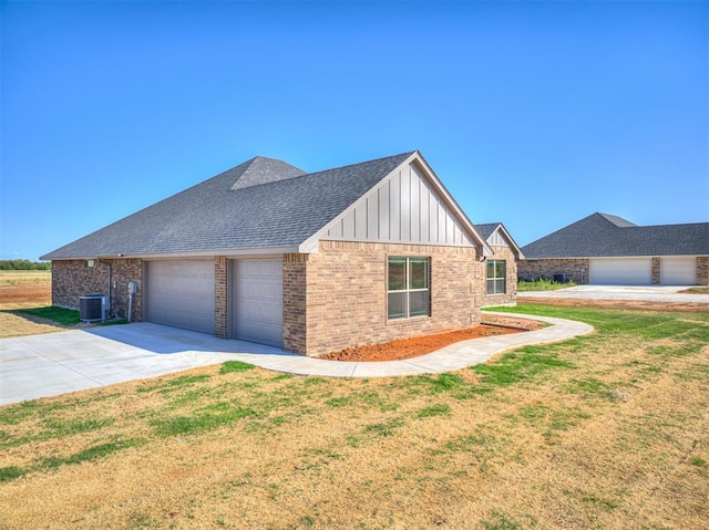 view of side of home featuring central AC unit, a garage, and a lawn