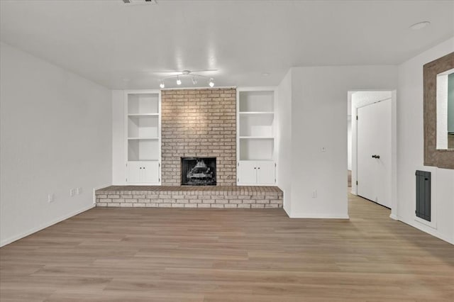 unfurnished living room featuring light hardwood / wood-style flooring, a fireplace, and built in shelves